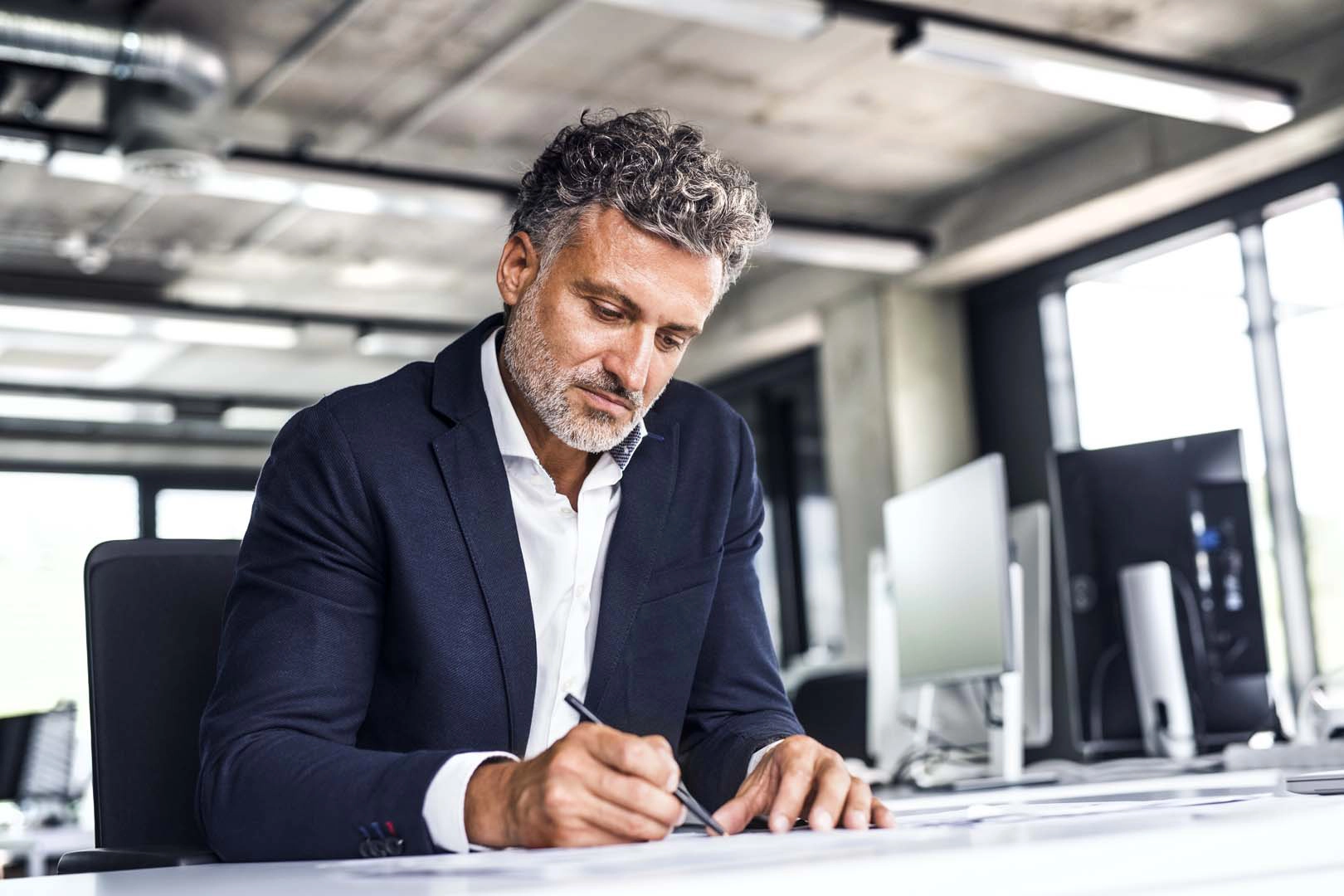 A man at a desk writes with a pen