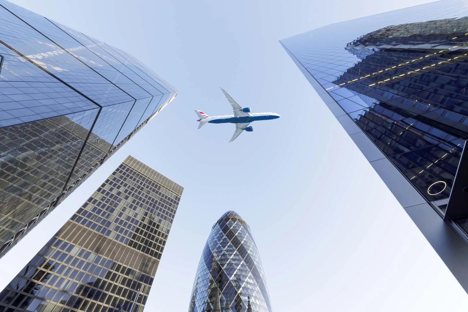 A plane fliest over the Gherkin in London