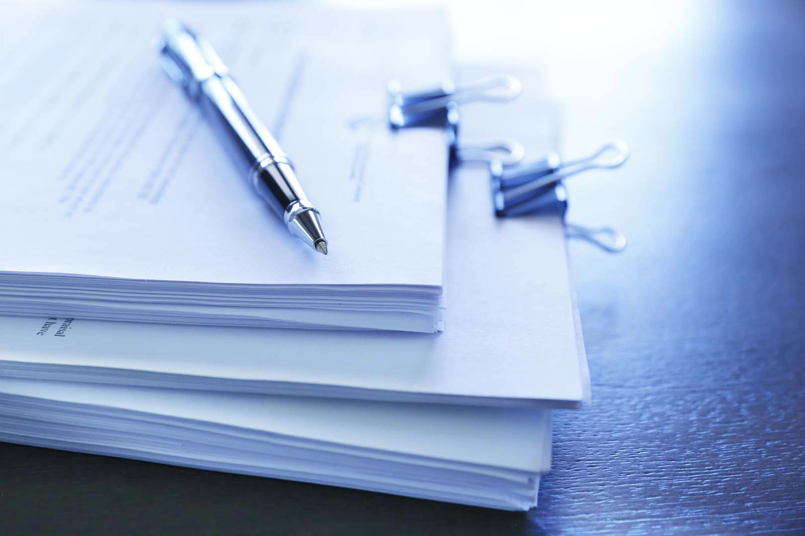 Bundles of papers clipped together with a pen on top
