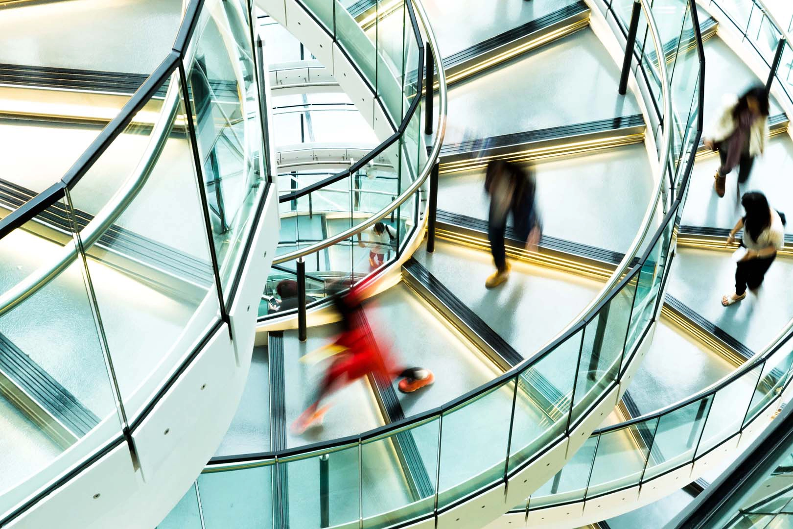 People in motion on spiral stair case in an office building