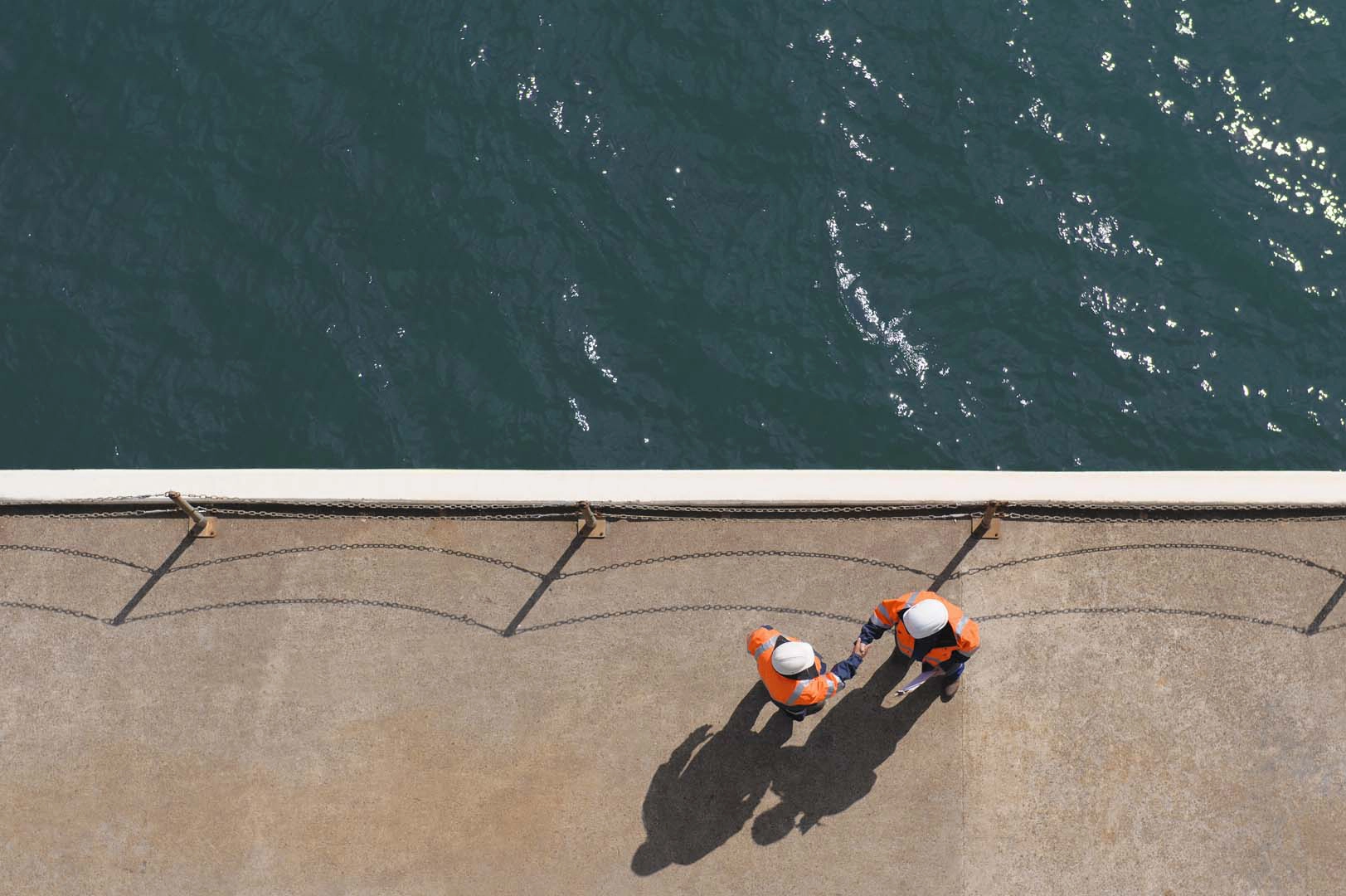 Two workers shake hands by reservoir