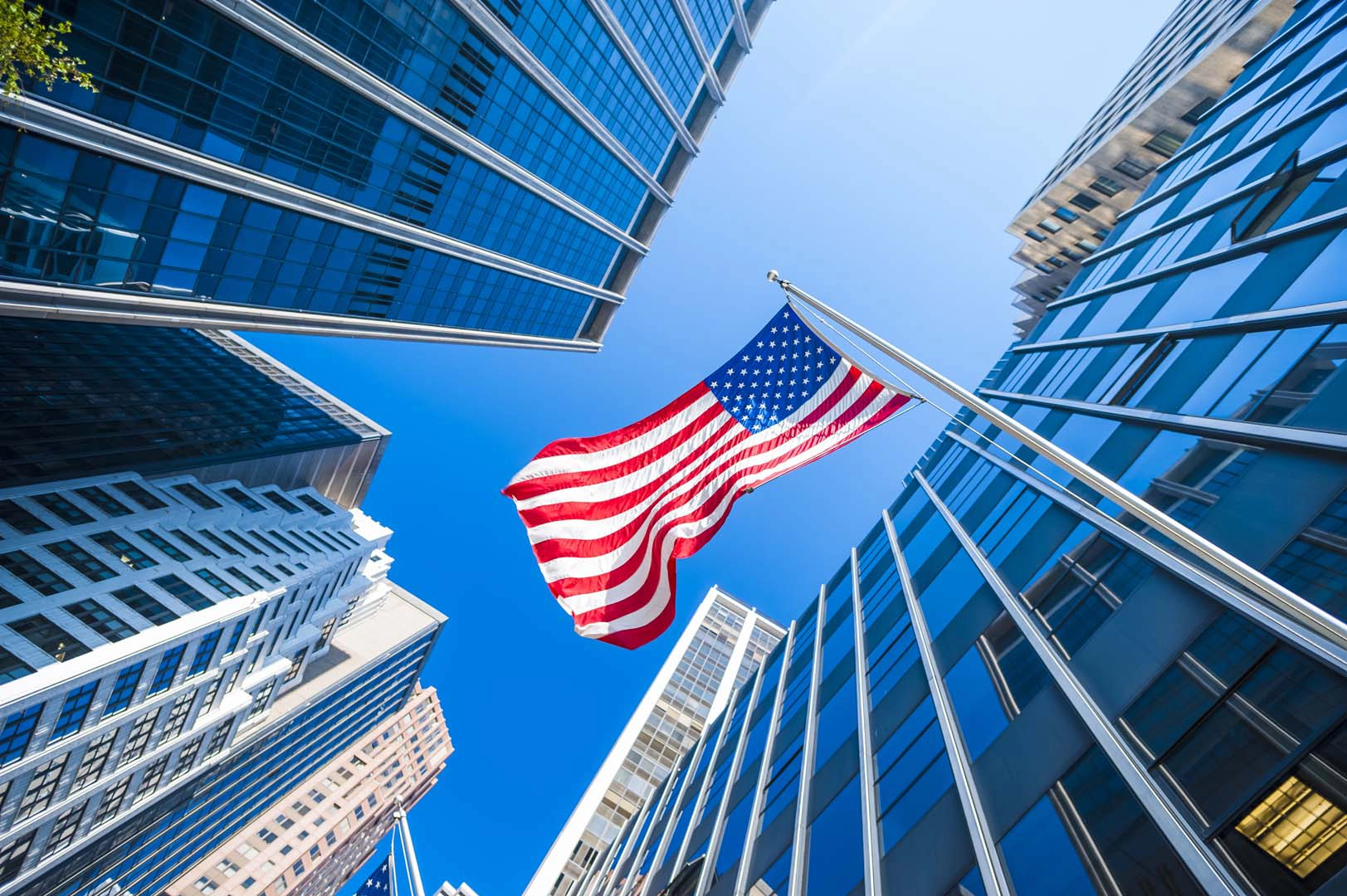 The American flag flies outside tall buildings. 